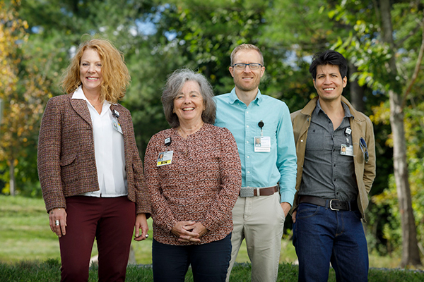 A group of four Dartmouth Health employees standing outside by trees