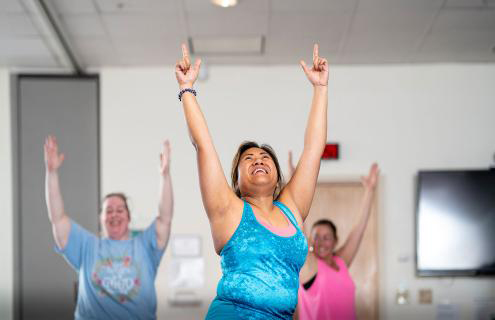 Three women in an exercise class with their arms held high