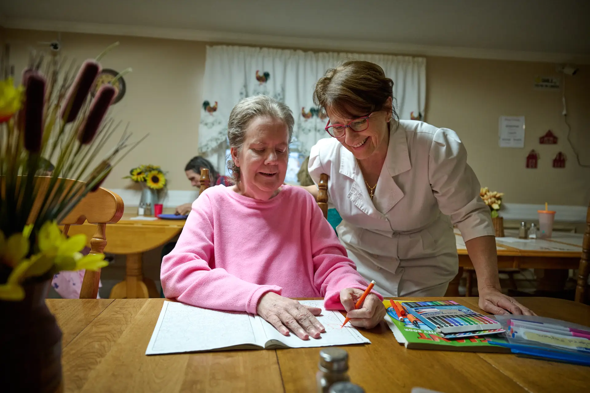 Susan Januszewski standing at a table with a friend who sits