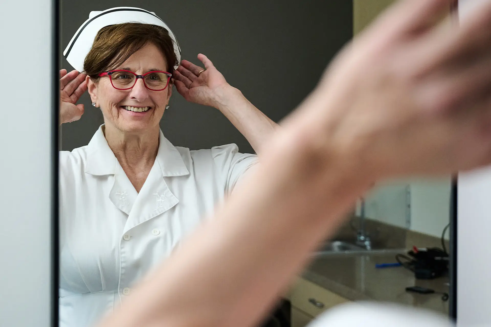 Susan Januszewski adjusts nurse hat while looking in the mirror