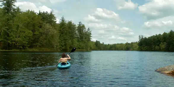 Patient Krystal Kebler seen from behind kayaking on a lake