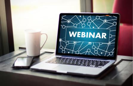 Laptop on a desk with the word "webinar" on the screen