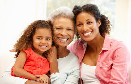 Image of a young girl, her grandmother and mother looking toward the camera and smiling