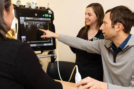 A provider giving a student a demonstration with orthopaedic imaging equipment