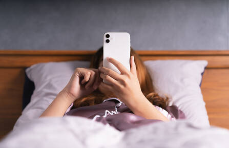 Woman using phone on bed after wake up