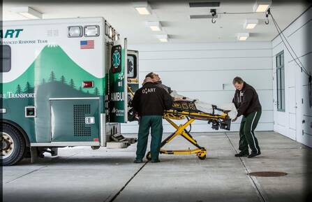 Two DHART employees load fellow employee posing as patient into the back of an ambulance on a stretcher