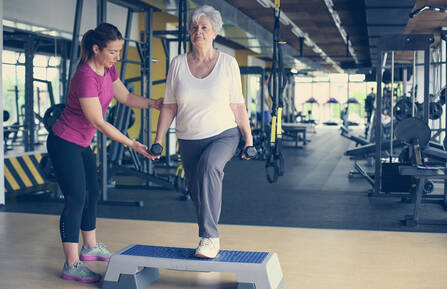 Personal trainer working exercise with senior woman in the gym