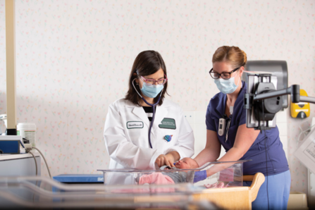 Two medical professionals attend to an infant
