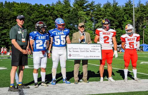 East-West All-Star Football Game Players holding donation check to Dartmouth Health Children's 