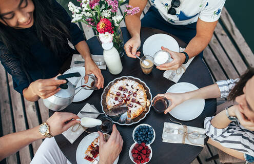 four people gathered around a table where pie is being served.