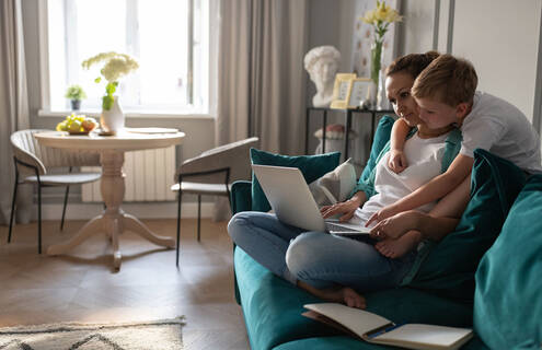 Child interrupting woman as she tries to work on computer