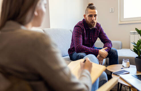 Young adult male speaking with female therapist