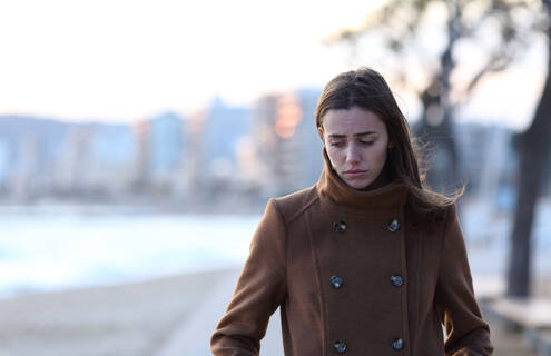 woman looking sad while walking on cloudy day in late fall