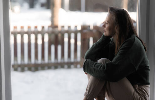 Woman looking out a window in winter