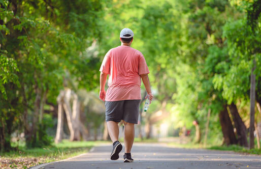 Man in workout clothes walking among trees seen from behind