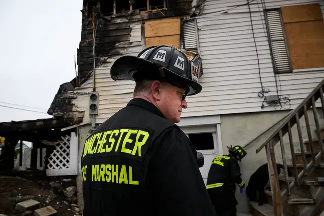 Patient Peter Lennon standing in front of a fire-damaged building