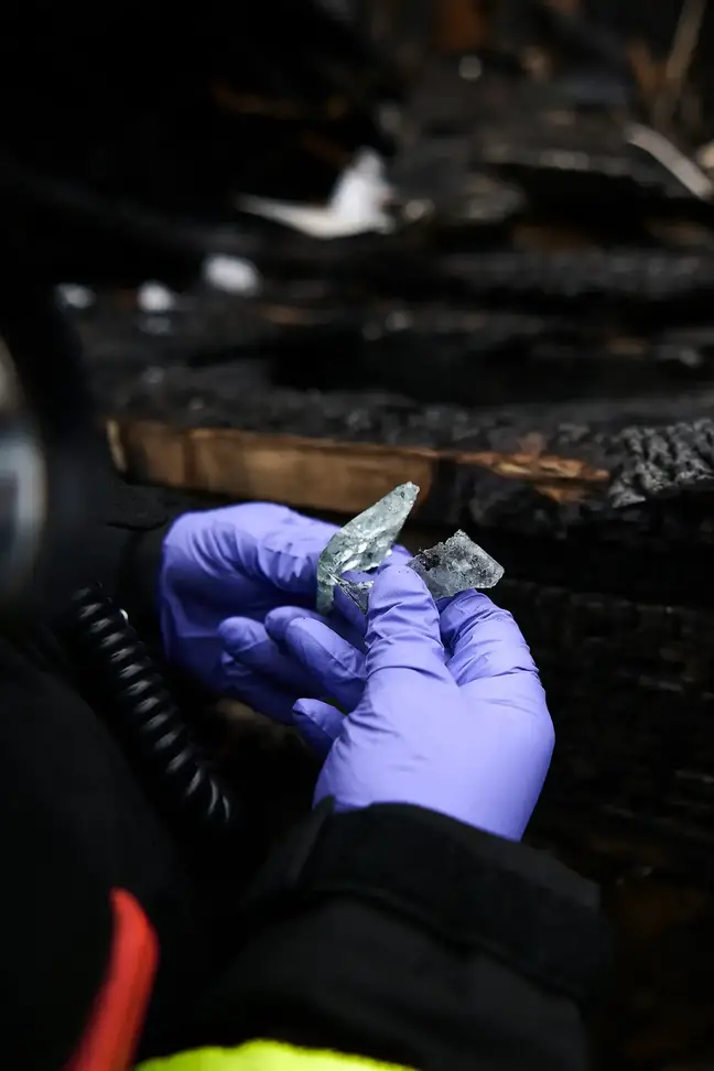 Closeup of patient Peter Lennon's gloved hands examining fire detritus