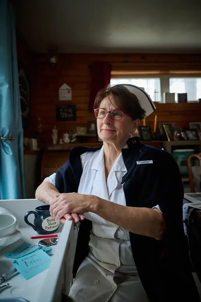 Nurse Susan Januszewski in her traditional nurses uniform, sitting at a table