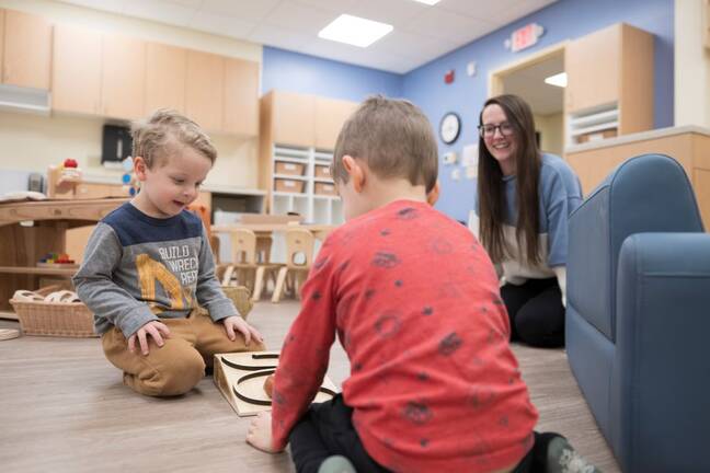 Young woman daycare provider in a child care room with two young children