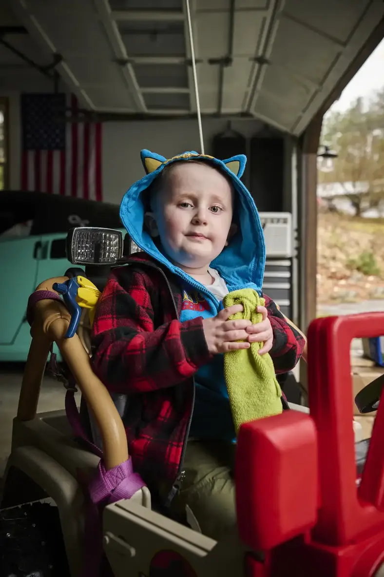 Connor Ponce looks at camera while sitting in his toy car